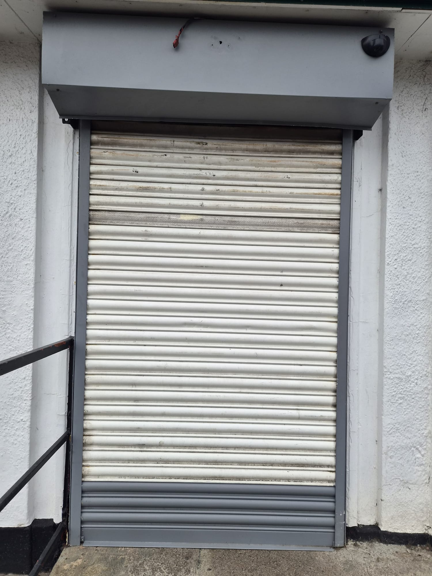 Pre-replacement view of weathered roller shutter to back-of-house unit