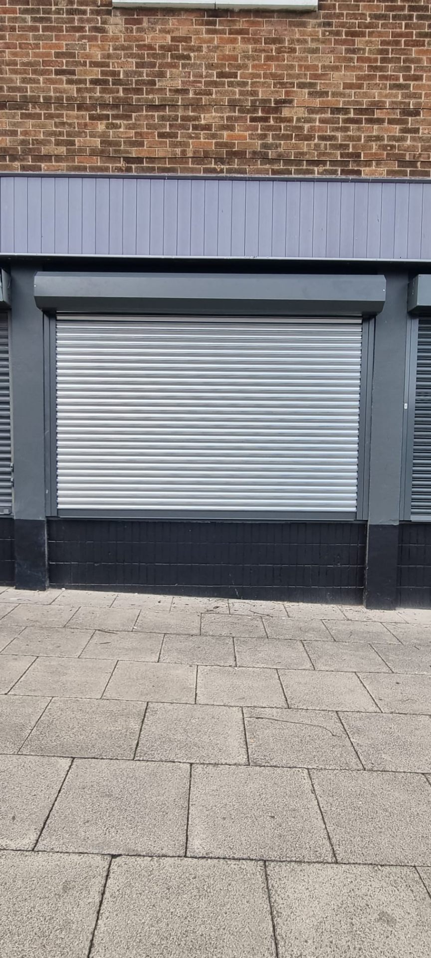 Single newly installed silver roller shutter to retail unit shopfront
