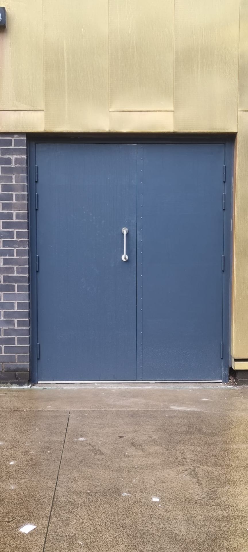 Single anthracite steel fire door with stainless pull handle, brick reveal