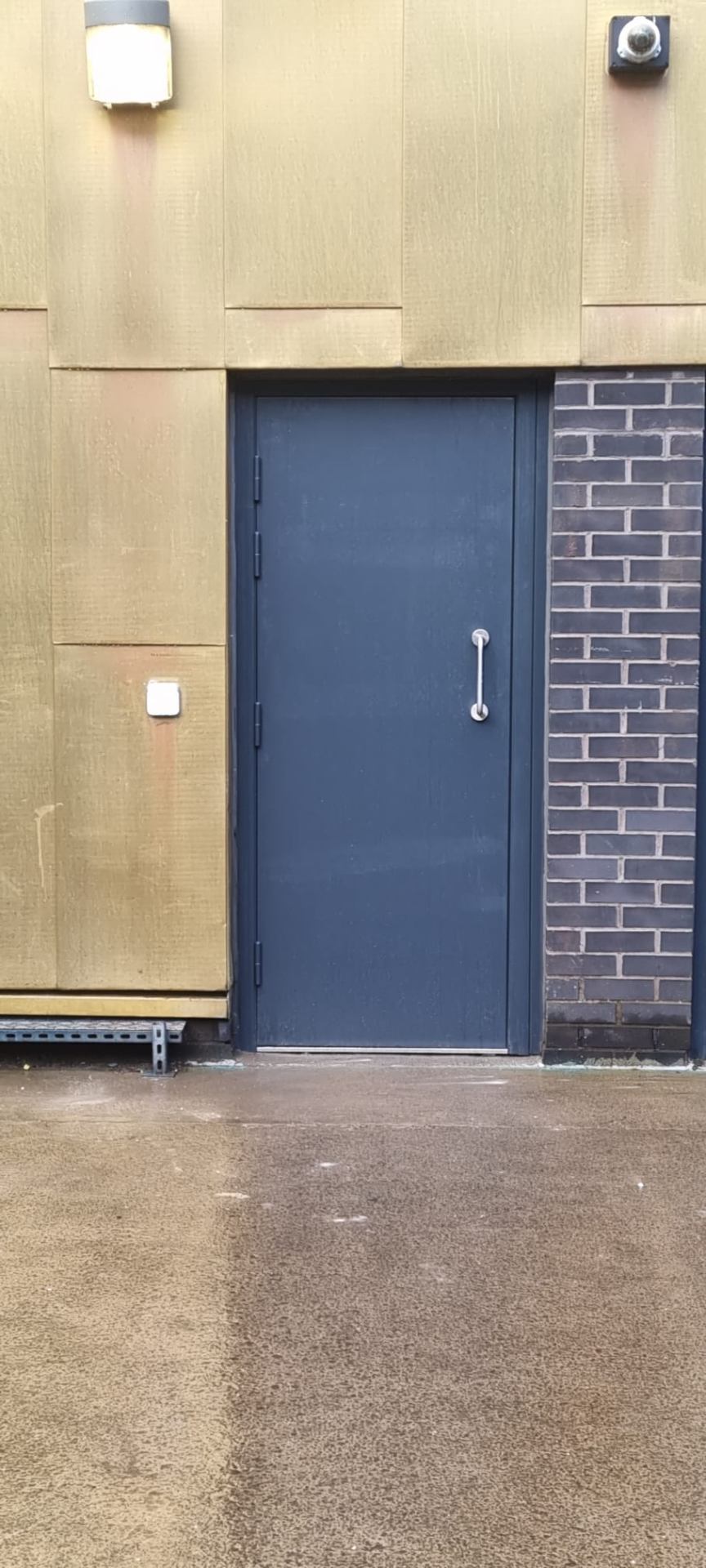 Single steel side fire door, anthracite, between brick and timber-clad façade