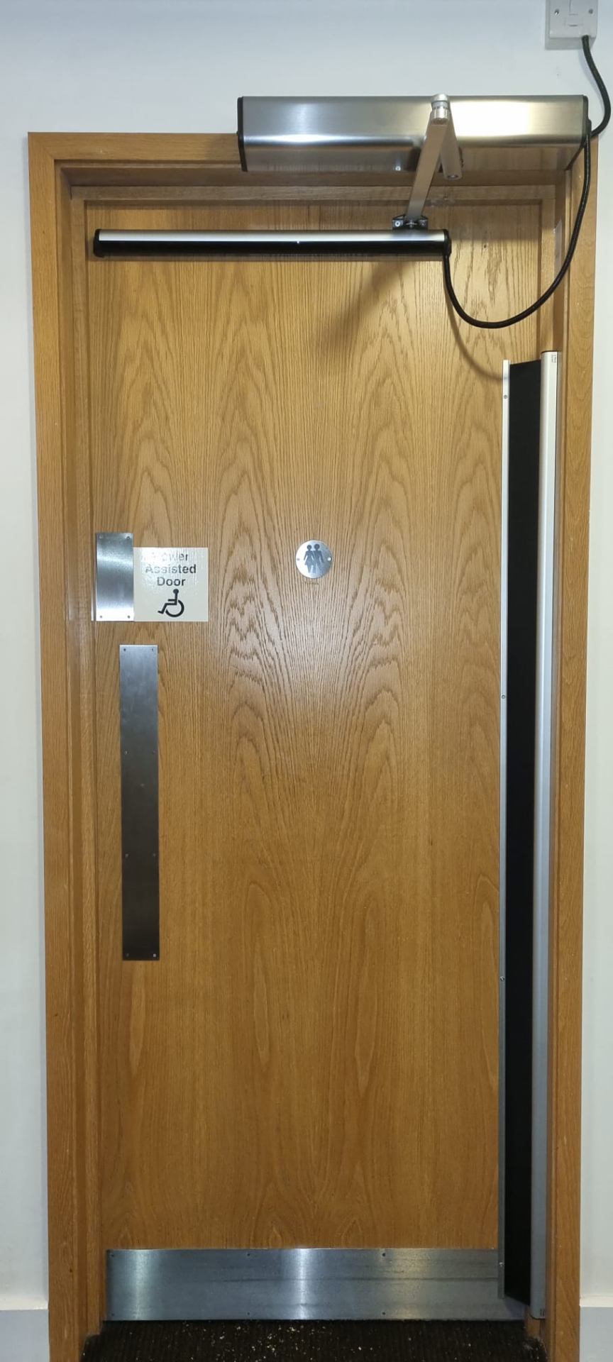 Power-assisted accessible oak timber door with overhead operator and push pad