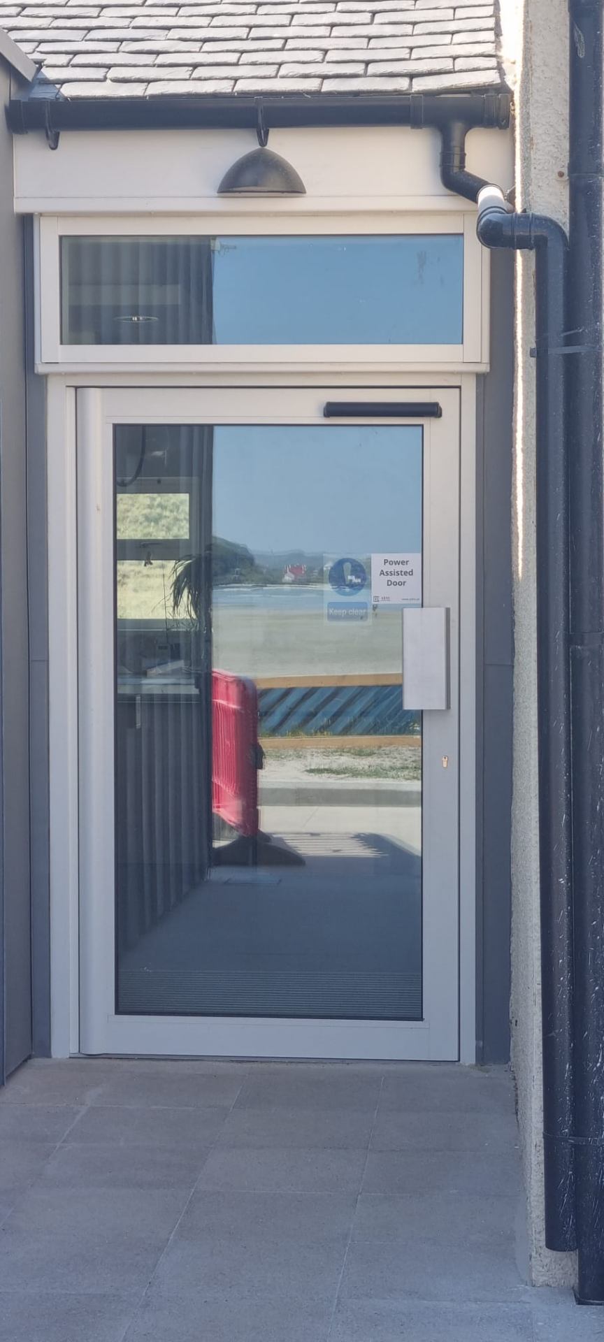 Power-assisted aluminium glazed entrance door at coastal commercial unit