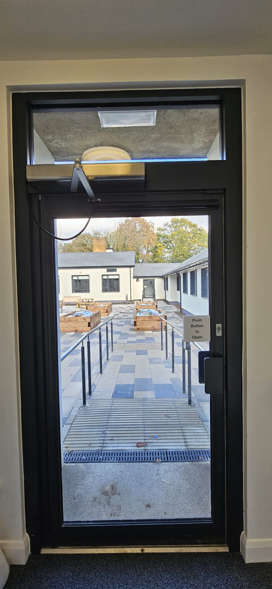 Single aluminium-framed automatic glazed entrance door with side-light, accessible threshold