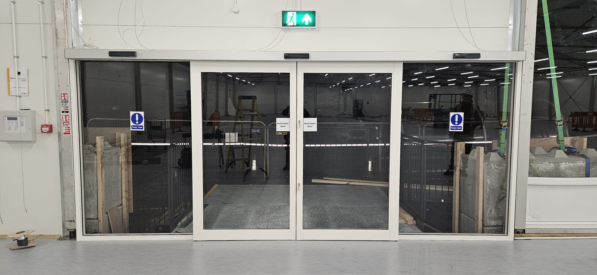 Twin pairs of automatic sliding doors at warehouse entrance — closed position