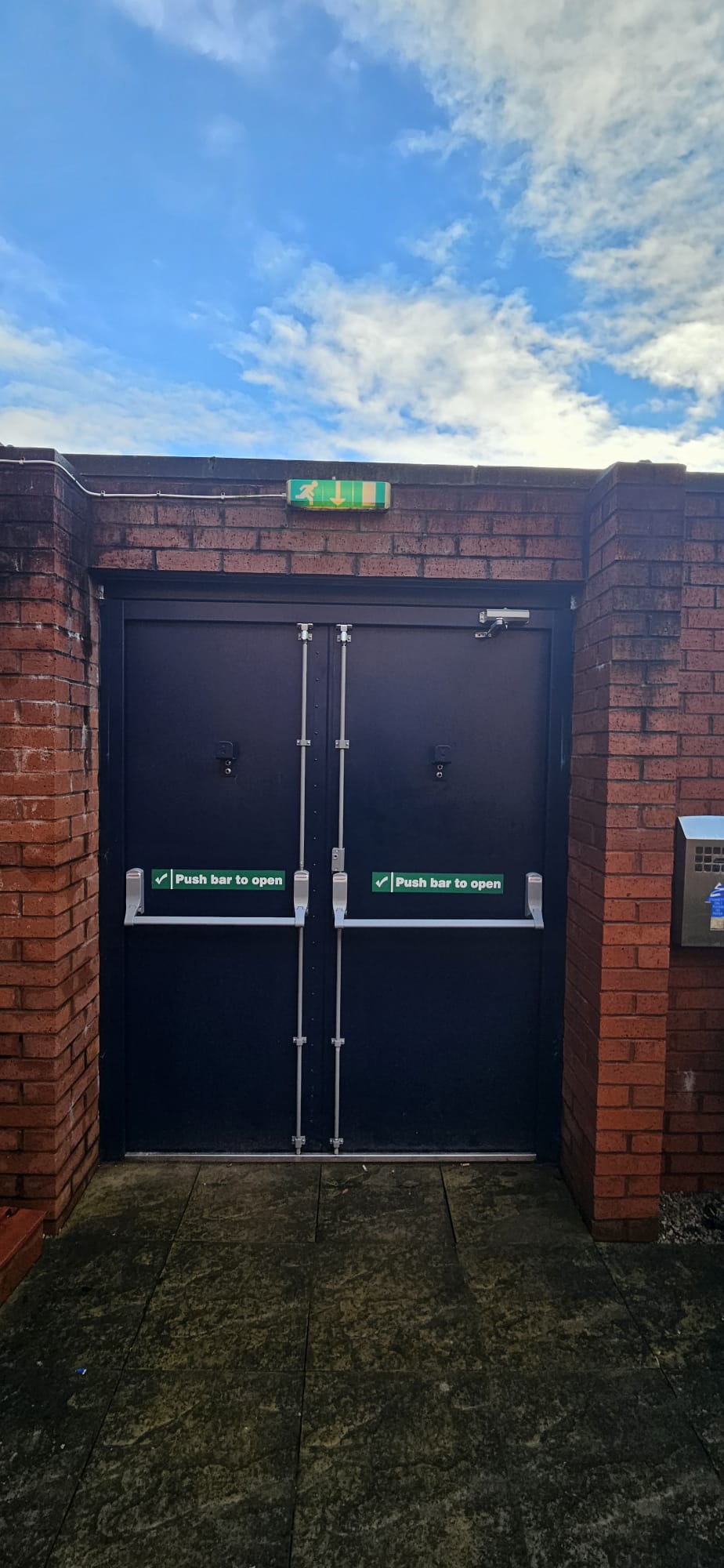 External steel double fire-exit doors with push bars in brick alcove