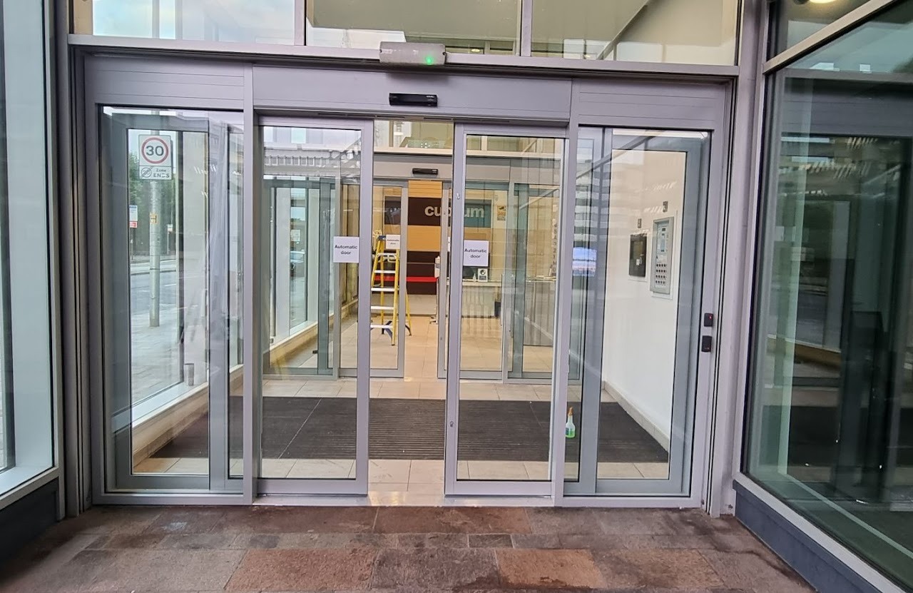 Aluminium-framed automatic sliding entrance doors with overhead access control reader and keypad