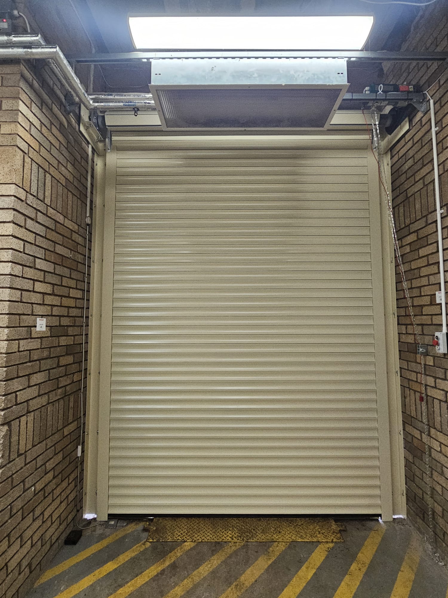 Cream insulated roller shutter to warehouse goods entrance with door curtain heater