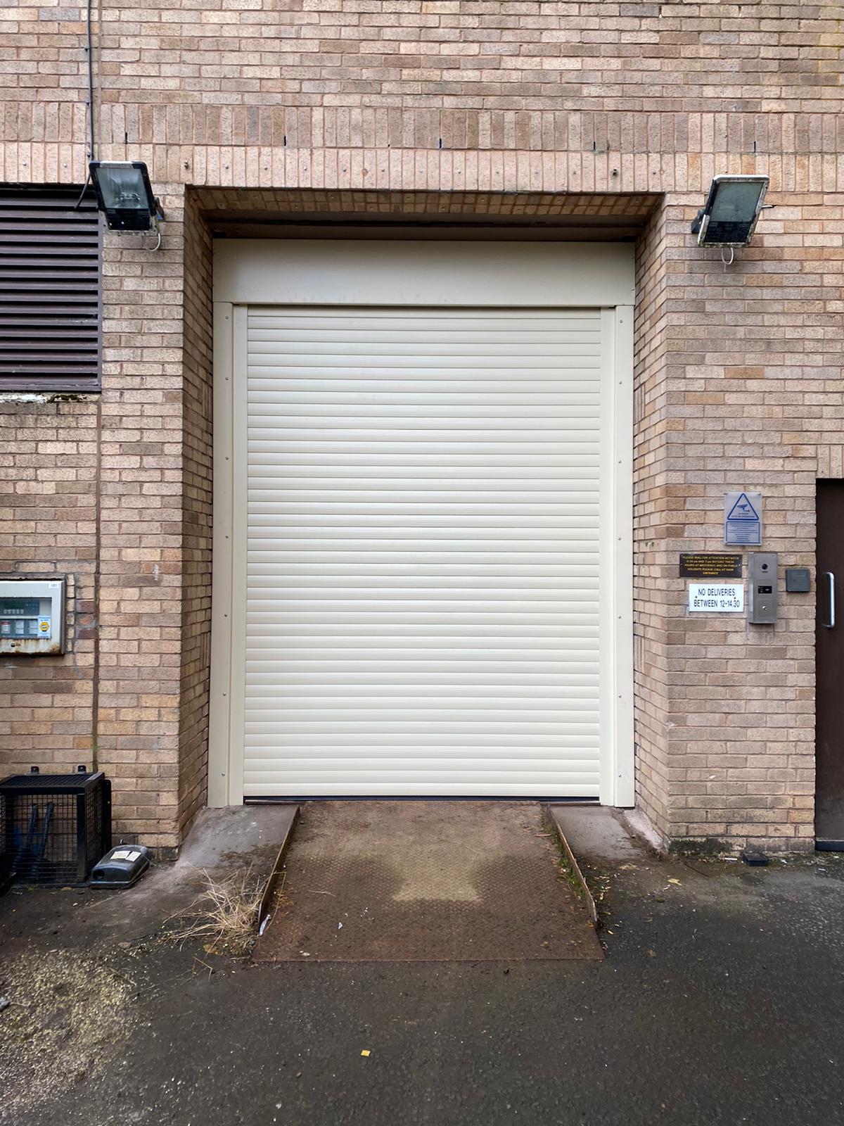 Cream industrial roller shutter to commercial loading bay with steel ramp