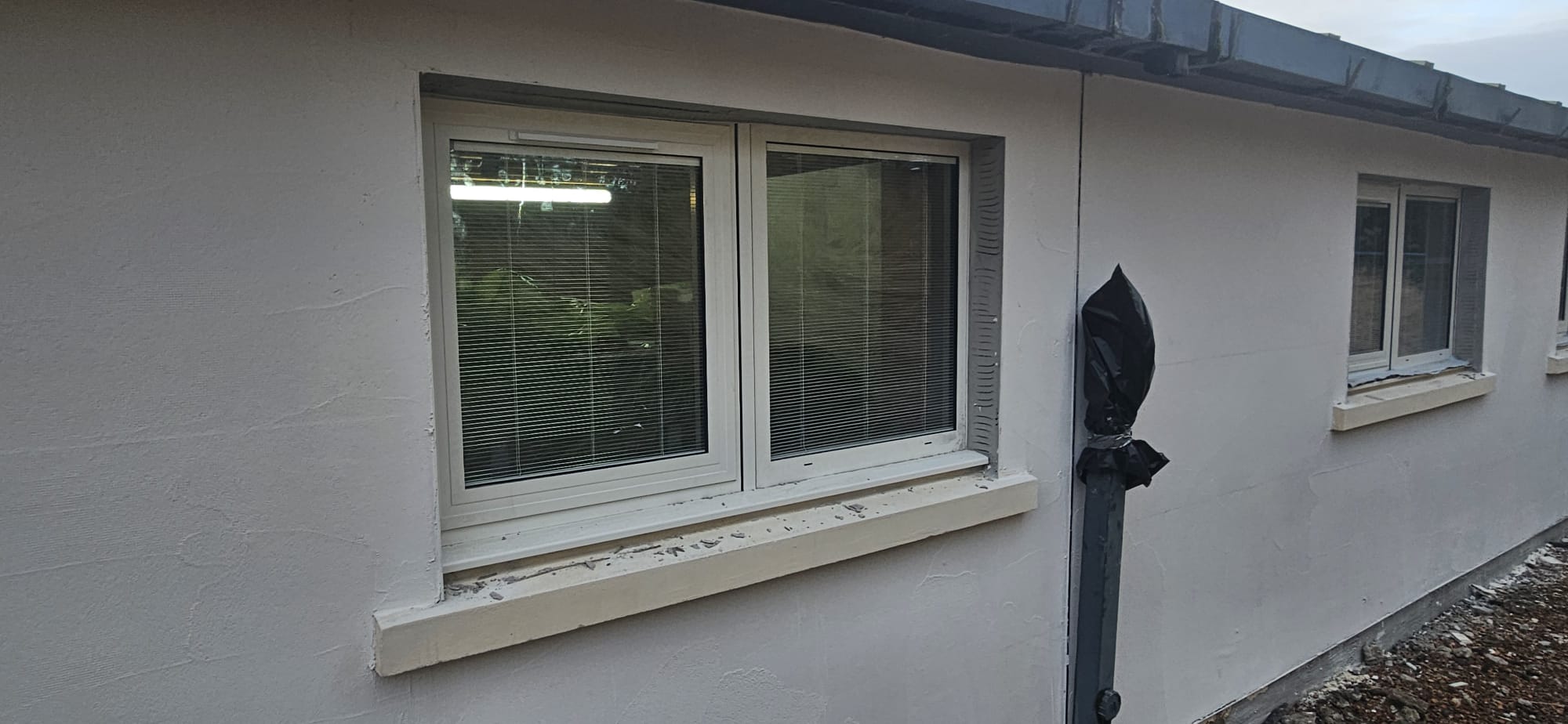Pair of UPVC-framed aluminium-clad windows with integral blinds, white render