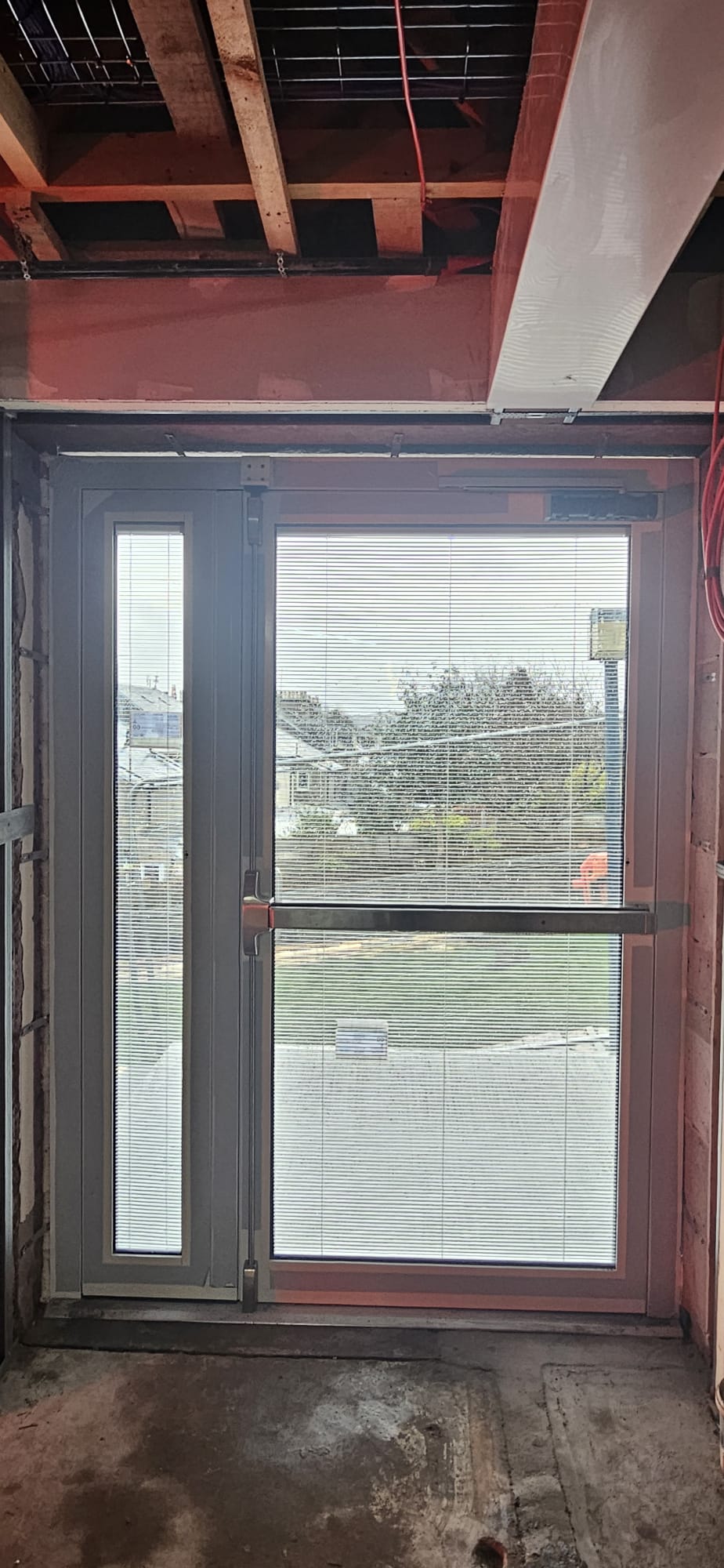Aluminium glazed double fire-exit doors with stainless push bar, integral blinds